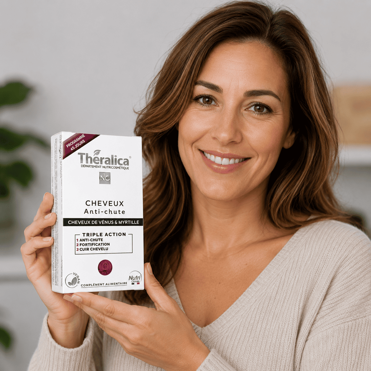 femme tenant dans sa main le complément alimentaire Cheveux Anti-Chute Theralica pour réduire la chute des cheveux et renforcer le cuir chevelu.